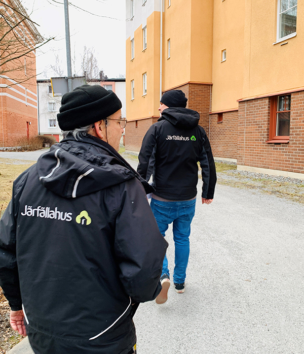 David och Henrik går över gården i jackor med Järfällahus logo på.