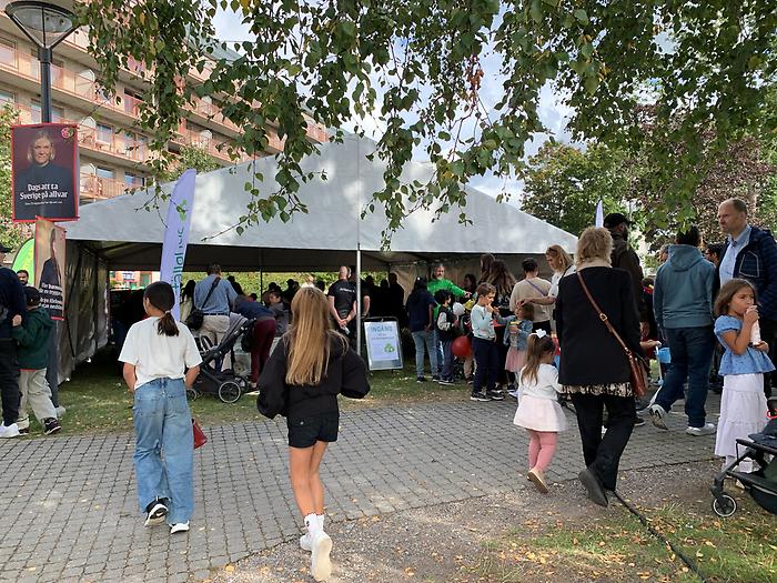 Människor myllrar kring ett vitt tält. Riddarstråket i bakgrunden.